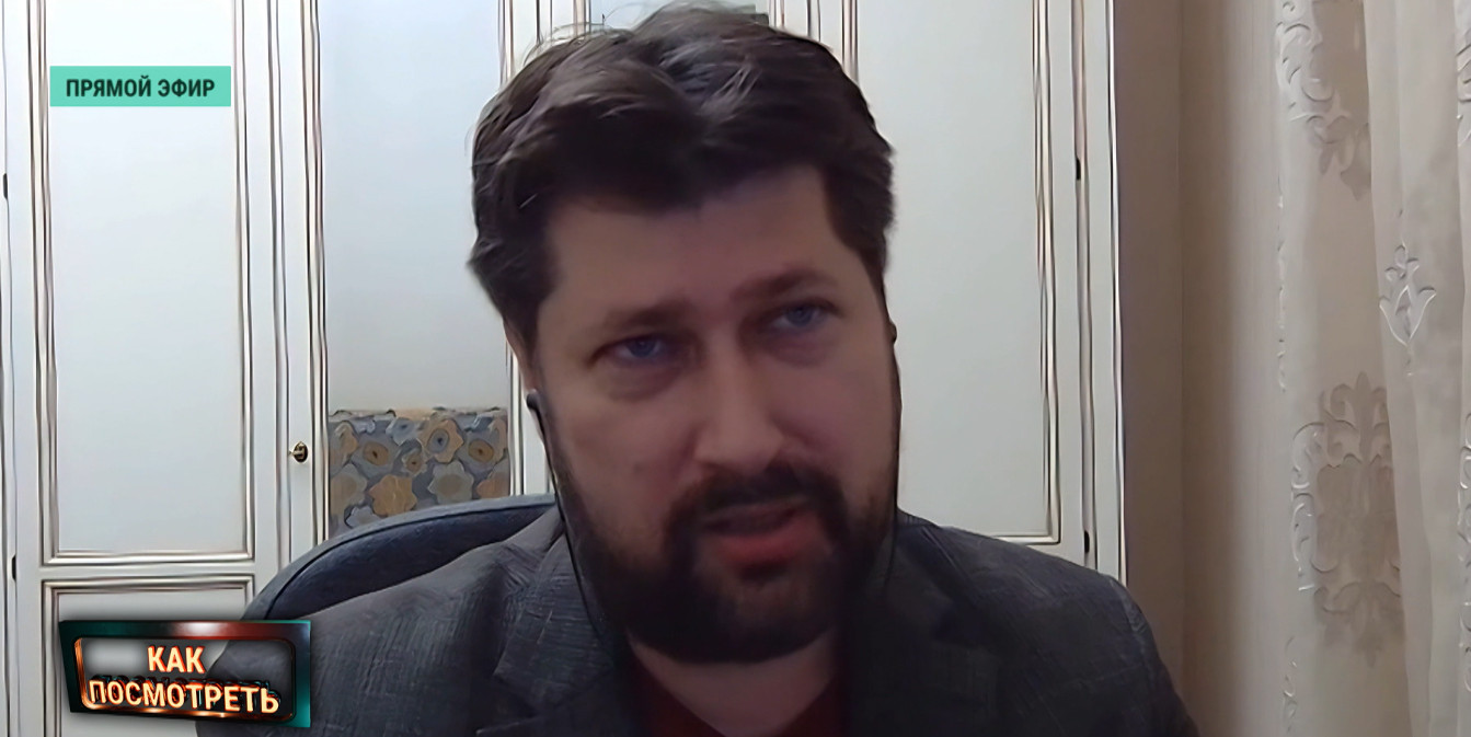 Василий Колташов дает интервью в прямом эфире аналитической программы «Как посмотреть». Кадр крупным планом, на фоне виден домашний или офисный интерьер.