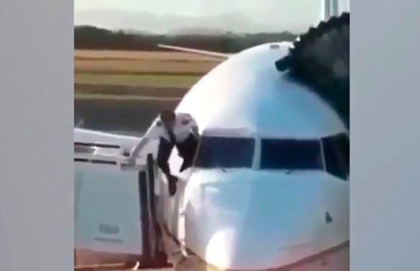 Пилот лезет в кабину самолёта через окно
